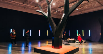 Huge black sculpted tree in middle of gallery.