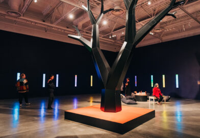 Huge black sculpted tree in middle of gallery.