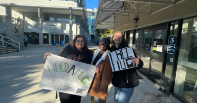 Three psychology students holding Free Hugs signs on VIU campus.