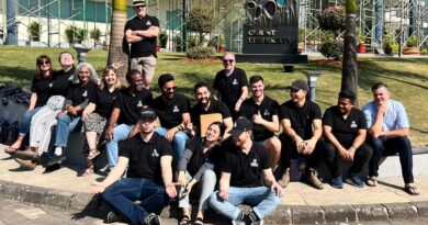 Team of 20+ youth in black t-shirts on lawn of building in India.