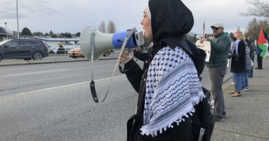 Woman in hijab with megaphone at protest.