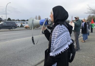 Woman in hijab with megaphone at protest.