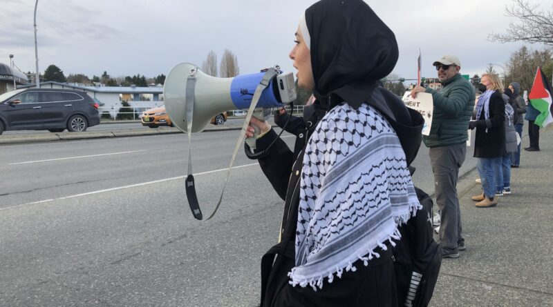 Woman in hijab with megaphone at protest.
