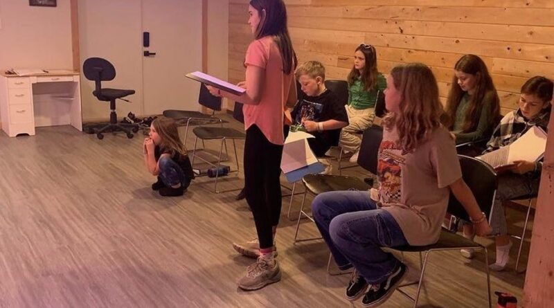 6-8 young students in Kismet studio holding scripts.