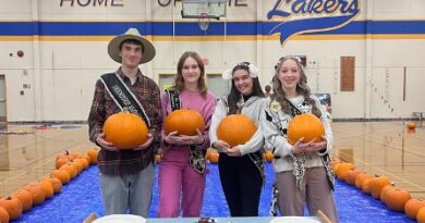 Four Cowichan Youth Ambassadors stand before a table holding pumpkins.