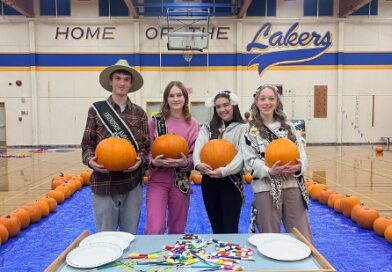 Four Cowichan Youth Ambassadors stand before a table holding pumpkins.