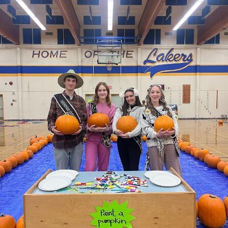 Four Cowichan Youth Ambassadors stand before a table holding pumpkins.