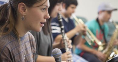3 20-something students holding a mic, clarinet or trumpet each.