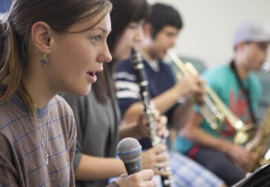 3 20-something students holding a mic, clarinet or trumpet each.
