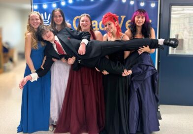 Five high school grads holding up a sixth, all in formal dress