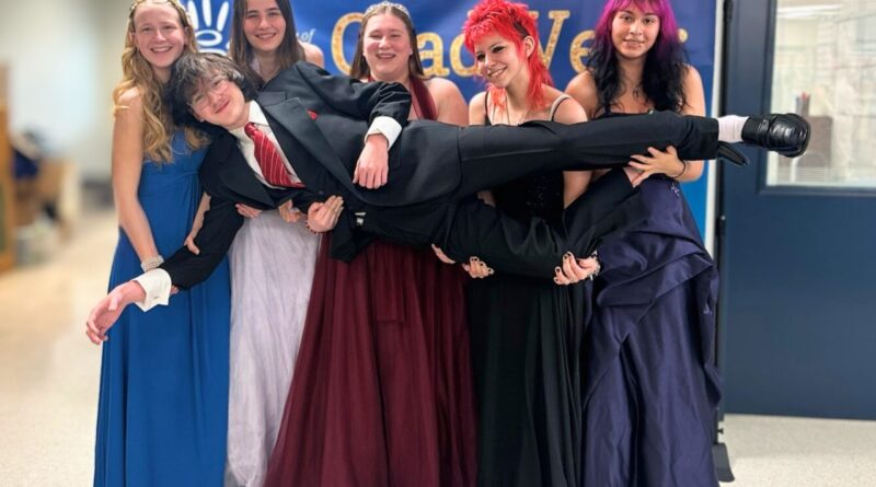 Five high school grads holding up a sixth, all in formal dress