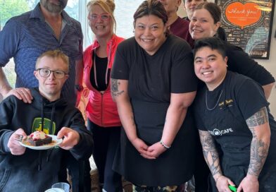 8 staff gathered around in a cafe