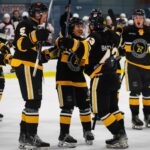 Nanaimo Buccaneers team on the ice in black and gold hockey uniforms