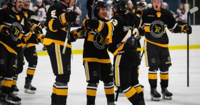 Nanaimo Buccaneers team on the ice in black and gold hockey uniforms