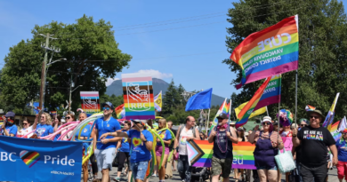 People of all ages in multicoloured outfits marching on the street for the Pride festival.