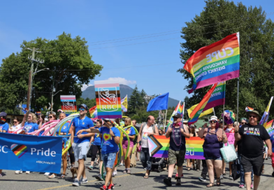 People of all ages in multicoloured outfits marching on the street for the Pride festival.