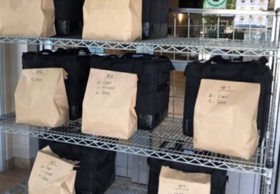 Brown paper bags of food on a shelf for pickup