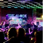 shot of the crowd and stage with musicians in background, neon colours