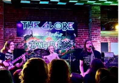shot of the crowd and stage with musicians in background, neon colours