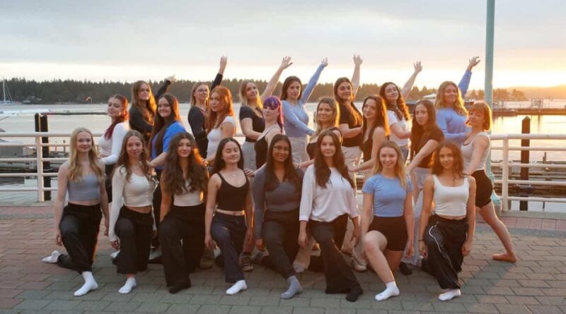 Two rows of women posing in dance wear on a pier outdoors
