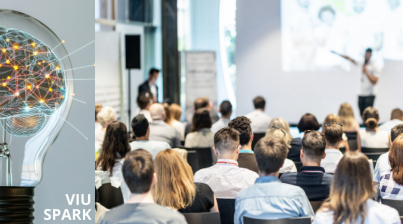 Audience in a white room looking at a stage